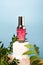 Cosmetic pink Serum bottle on Blue Background. Beauty wellness natural concept. Square cube Podium with green leaves