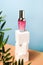 Cosmetic pink Serum bottle on Blue Background. Beauty wellness natural concept. Square cube Podium with green leaves