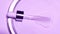 The cosmetic pipette with natural liquid on pale purple colored background