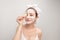 Cosmetic procedures. Woman with cosmetic mask on face eats cucumber slice