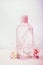 Cosmetic product bottle with micellar water or tonic for skin care, pink flowers, pastel color, front view.