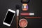 Cosmetic products and accessories on black background. Mobile phone with blank screen. Top view and copy space