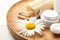 Cosmetic products, chamomile and loofah on plate, closeup