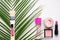 Cosmetic products with perfume bottle and tropical leaf on white background