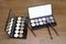 Cosmetic sets with eye shadows and brushes in black plastic case with mirror on wooden background