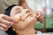 Cosmetician massaging the client face with acupressure metal roller massagers