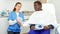 Cosmetician woman with papers talking to man before procedure in clinic