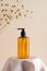 Cosmetics amber glass bottle on podium and dry grass on beige background. Soap dispenser, shower gel, shampoo container design on