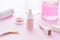 Cosmetics bottles on the pink background with flowers.