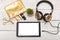 Cosmetics, gold headphones and gold cosmetic bag on a white wood