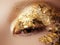 Cosmetics and make-up. Closeup macro shot of fashion sparcle visage. Closeup portrait of beautiful young woman with golden foil o