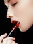 Cosmetics and makeup. Perfect lip makeup. Fashion model applying lipstick. Beautiful young woman