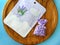 Cosmetics mockup with nourishing sheet mask package on a wooden oak plate with lavender flowers small pouch.