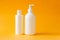 Cosmetics, moisturizer, two white plastic bottles with shower gel and shampoo on yellow background. Set of body and hair