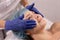 Cosmetologist in blue gloves does facial massage. Woman enjoys the procedure. Anti-aging massage. Cosmetic procedures