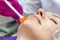 Cosmetologist doctor applies gel to the patient`s face with a brush in a beauty salon. Preparation for the procedure of