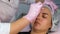 Cosmetologist doctor is wiping woman's forehead with antibacterial liquid.