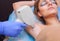 The cosmetologist does the laser hair removal procedure in the armpit zone, to a young woman