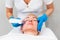 A cosmetologist does an ultrasound facial cleansing for an adult Caucasian woman. Hardware anti-aging cosmetology