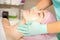 Cosmetologist with gloved hands applies a moisturizing mask with peeling cream on the female face. Facial cosmetology