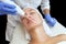 The cosmetologist makes the procedure Microcurrent therapy of the facial skin of a beautiful, young woman in a beauty salon