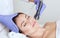 The cosmetologist makes the ultrasonic cleaning procedure of the facial skin of a beautiful woman in a beauty salon