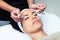 Cosmetologist making the eyes contour therapy for rejuvenation to woman on the spa center