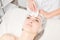 Cosmetologist making facial massage with Gua Sha stone of woman face skin for lymphatic drainage