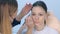 Cosmetologist painting brush shape of eyebrows woman before tint procedure.