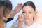 Cosmetologist painting brush shape of eyebrows woman before tint procedure.