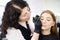 Cosmetologist painting eyebrows by brush. Attractive woman getting facial care and makeup at beauty salon. Architecture eyebrows