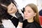 Cosmetologist painting eyebrows by brush. Attractive woman getting facial care and makeup at beauty salon. Architecture eyebrows