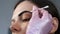 Cosmetologist is painting woman's eyebrows in cosmetology clinic, closeup view.