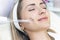 Cosmetologist performs a pulse current procedure for the face of a young woman
