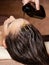 Cosmetologist pours balm for hair on head of  woman. Spa treatments