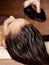 Cosmetologist pours balm for hair on head of  woman. Spa treatments