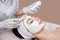 The cosmetologist for procedure of cleansing and moisturizing the skin, applying a Alginic mask to the face of a young woman in be