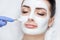 The cosmetologist for the procedure of cleansing and moisturizing the skin, applying a mask with stick to the face