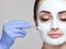 The cosmetologist for the procedure of cleansing and moisturizing the skin, applying a mask with stick to the face