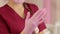 Cosmetologist puts on pink protective gloves before the procedure of sugaring.