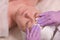 Cosmetologist`s hands in purple gloves wiped the female forehead with cotton pads. Cosmetic procedure for the skin of the face