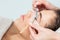 Cosmetologist`s hands wiping eyelashes of woman