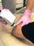 A cosmetologist, a specialist doctor, conducts a cosmetology procedure of laser rejuvenation of the elbows to the patient with his