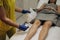 Cosmetologist is sprinkling and distributing talcum powder on a young girl& x27;s leg before the epilation procedure. The