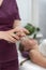 Cosmetologist treats the hands before the procedure. Masseur applies the oil to the hands to perform the massage. Close up