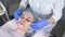 Cosmetologist wipes the face of a young woman with cotton pads. Hands of the beautician in gloves and a face closeup