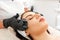 Cosmetology and beauty procedures. Professional beautician gives a facial massage with jade stones to the client in