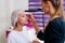 Cosmetology cabinet client sitting on couch. Beautician applies marking on eyebrows