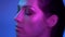 Cosmical fashion model in profile in purple neon lights turns leftwards and raise her head with satisfaction.