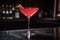 A cosmopolitan cocktail sitting on a bar in a nightclub